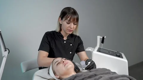 The specialist cleans the face of a lady with the help of the oxygen procedure Video stock 228567645