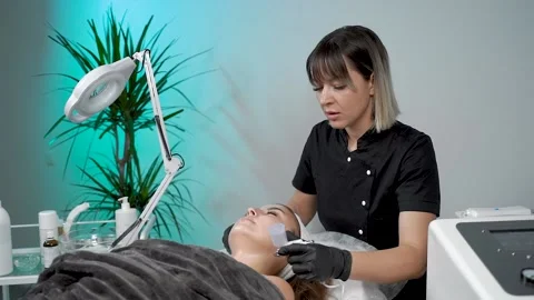 The specialist cleans the face of a lady with the help of the oxygen procedure Stock Footage 228567699