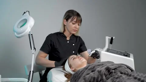 The specialist cleans the face of a lady with the help of the oxygen procedure Stock Footage 228567790