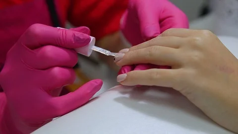 Specialist covers the nail of the client by fixer. Close up Stock Footage 97197784