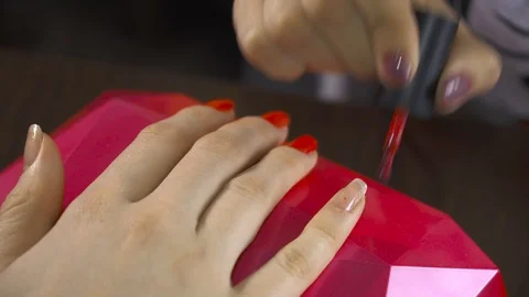 The specialist covers the nail of the client with red lacquer and corrects mista Stock Footage 104158087