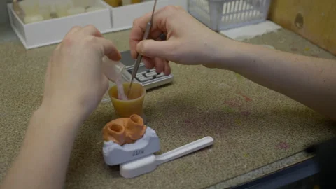 Specialist creating the dental plaster mixture inside of the small plastic cup Stock Footage 249397150