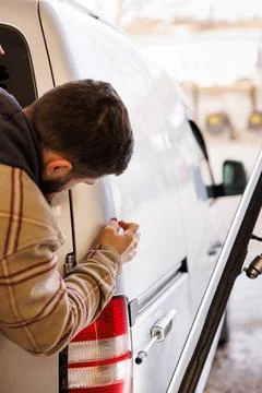 A specialist examines the damage caused by a small accident to the rear wing of Stock Photos