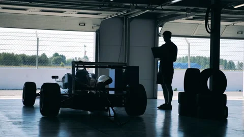 A specialist with a laptop is visually inspecting a racing car Stock Footage 165198898