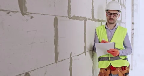 Specialist makes notes examining cinder blocks wall in apartment Stock Footage 309081234