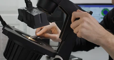 Specialist or gemologist looking through a microscope to examine diamond Stock Footage 247375552