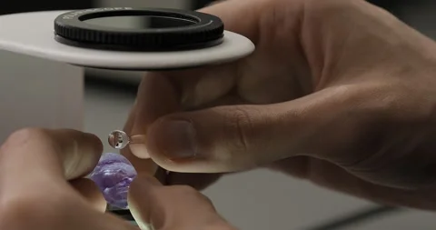 Specialist or gemologist looking through a magnifier to examine violet gem Stock Footage 247391045