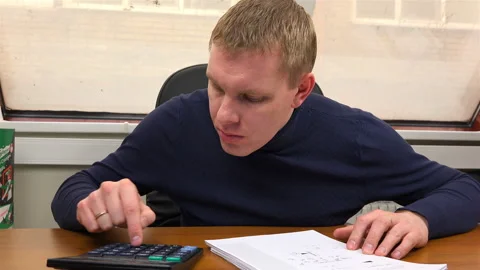 The specialist performs the calculation on the calculator according to the Stock Footage 99947065