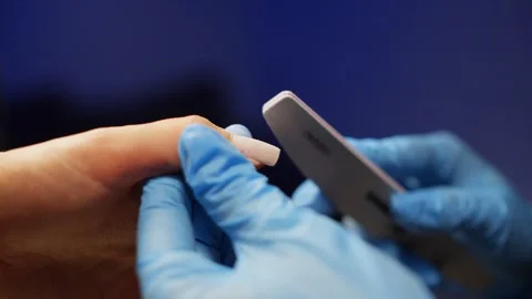 A specialist in protective gloves files the gel with a file during a manicure. Stock Footage 325569766