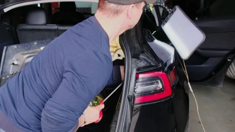 Specialist pushes dent out using tool looking at reflector board Stock Footage 316175958