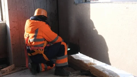 Specialist squats on floor controls mounting wall in house Stock Footage 124892423