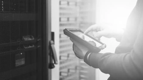Specialist with a tablet in server room, checking the status of critical syst Fotos Stock