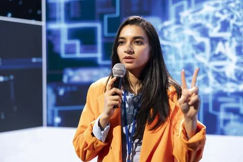 Specialist talking in mic at technology summit, explaining impact of AI Stock Photos