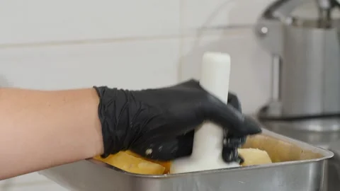 Specialist uses potato masher to process boiled potatoes to create potato mix Video stock 322940256