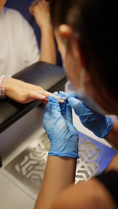 The specialist is very careful when working on the cuticle with manicure machine Stock Footage 343532426