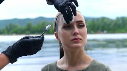 The specialist washes off the paint from the eyebrow of the model with a special Stock-Footage 202010088
