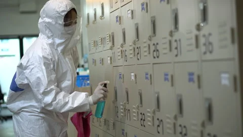 Specialist wearing ppe suit using alcohol sanitizer spray to clean the locker Stock Footage 136355520