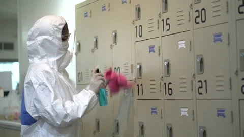 Specialist wearing ppe suit using alcohol sanitizer spray to clean the locker Stock Footage 137950338