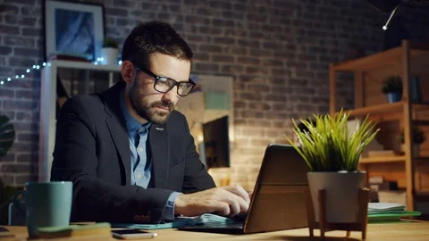 Specialist young man using laptop in dark office smiling feeling happy at work Stock-Footage 118605107