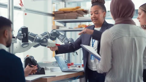 Specialists And Mentor Looking At Robot Hand An Discuss Stock Footage 187569582