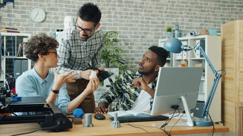 Specialists discussing 3d printed shape using computer and 3d printer in office Stock Footage 119565178