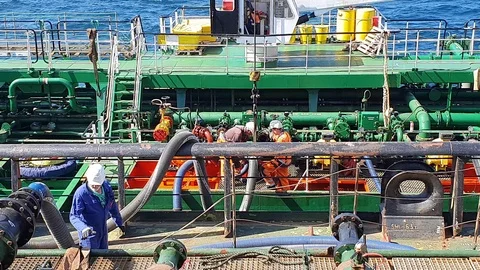 Specialists in jumpsuits and helmets work with black pipe Stock Footage 113193935