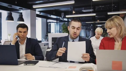 Specialists sharing contract or document with colleagues sitting Stock Footage 119421243