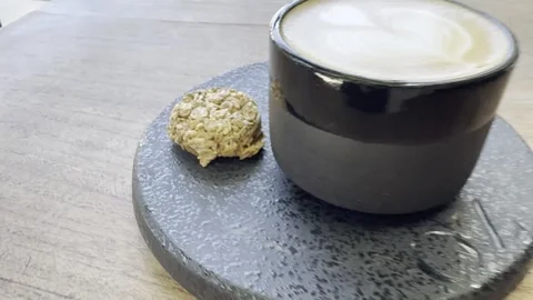 Specialty Oat Milk Latte with Biscuit on Café Table Stock Footage 338070569
