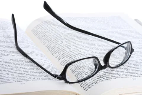 Spectacles lying on the opened book Stock Photos