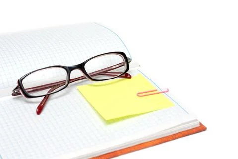 Spectacles on note pad Spectacles on note pad with yellow bookmark and ros... Stock Photos