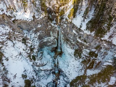 Spectacular drop down view of waterfall falling over rocky forest ledge. Stock Photos