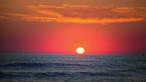 Spectacular orange sunset over calm sea with glowing sun and dramatic clouds Stock Footage 335306129