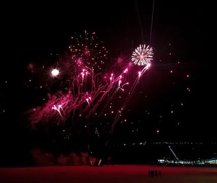 Spectacular pink fireworks explode against a dark night sky, illuminating a.. Stock Photos