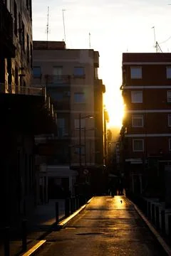 Spectacular sunset with the sun getting between the buildings Stock Photos
