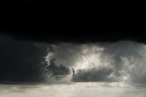 Spectacular thunderclouds with sunlight breaking through them in the dark sky. Stock Photos