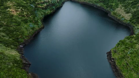 Spectacular top-down aerial drone view of a dark volcanic crater lake nestled 库存影片 335710697