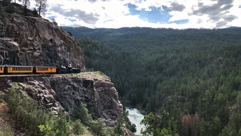 Spectacular view as train clings to a mountainside cliff over a deep river gorge Stock Footage 113875955