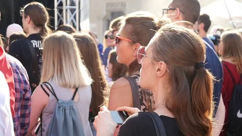 Spectator fan girl in front of concert stage raise hands hold mobile phone shoot Stock Footage