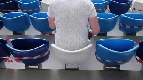 A spectator at the stadium sits down in his seat. Social distance on mass event Stock Footage 139932566