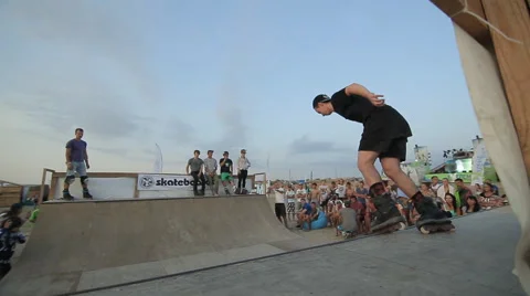 Spectators Are Watching as a Teenager Doing Rollerskating tricks in the ramp Stock Footage 59888568