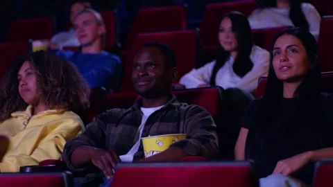 Spectators in a cinema in the middle ground are watching a film, a pleasant Видео 267350138