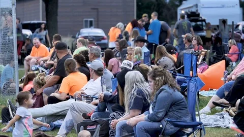 Spectators gather to watch small town coed softball game summer celebration Stock Footage 77845331