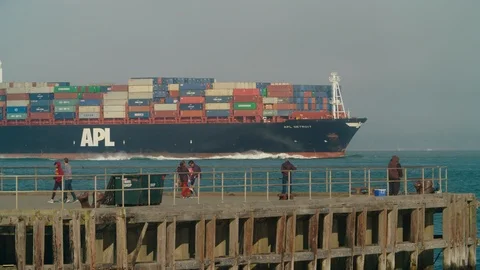 Spectators on a pier watch a large cargo ship approaching the Golden Gate Bridge Stock Footage 93840920