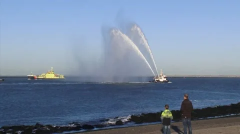 Spectators on quay, fireboat performs a water salute - long shot Stock Footage 47630821