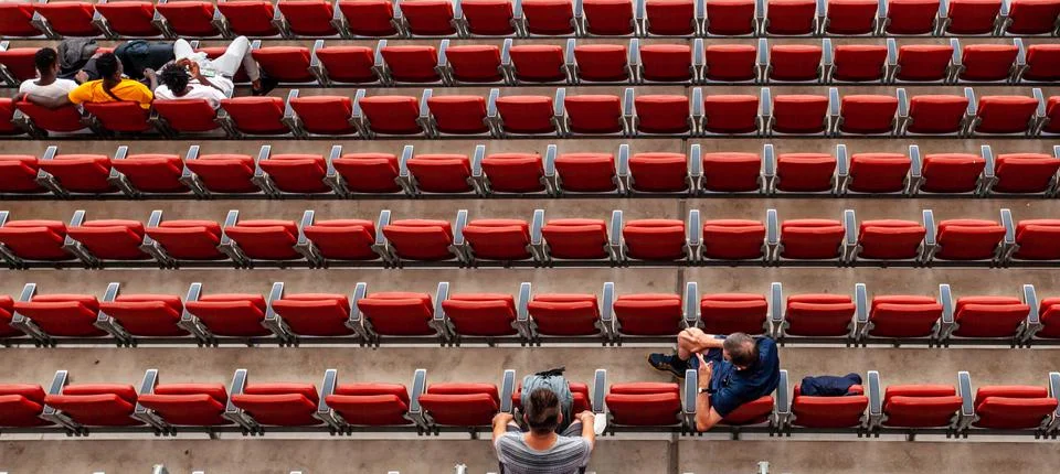 Spectators at the stadium in red seats are watching the match Stock Photos