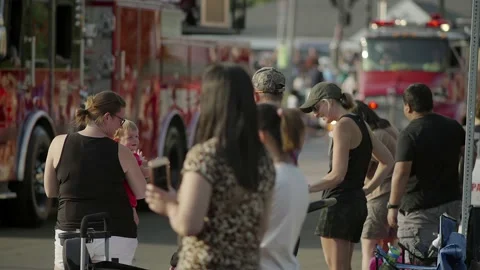Spectators watching a parade of fire trucks traveling past, in slow motion. Video stock 162639262