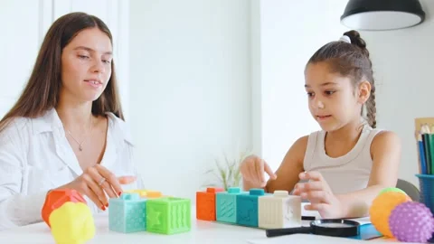 Speech therapist engages with child using colorful building blocks to enhance Stock Footage 315538560