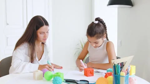 Speech therapist engages with child using colorful toys and art supplies in a Stock Footage 315540949