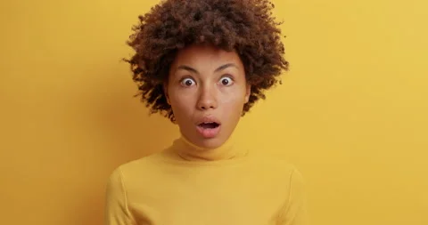 Speechless impressed curly haired young woman stares in disbelief has bugged Stock Footage 142332947