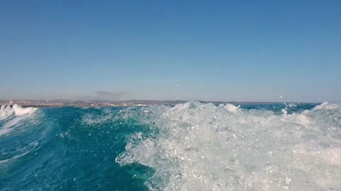 Speed boat generating wake trail and water spray on sea surface. Low-angle Stock Footage 142772048